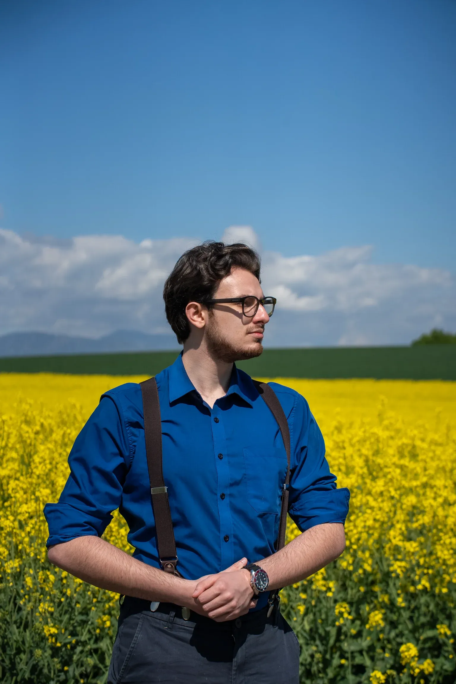 Charles Lindecker, chemise bleu roi, dans un champ de colza en fleur.